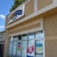Storefront of a shop with large glass windows and a colorful sign reading '... & Minifigs' under a clear blue sky; street numbers 3670 and 3660 visible.
