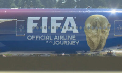 Blue airplane fuselage with a large 'FIFA' logo and a gold skull-like figure on the nose, plus the text 'Official Airline of the Journey'.