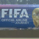Blue airplane fuselage with a large 'FIFA' logo and a gold skull-like figure on the nose, plus the text 'Official Airline of the Journey'.