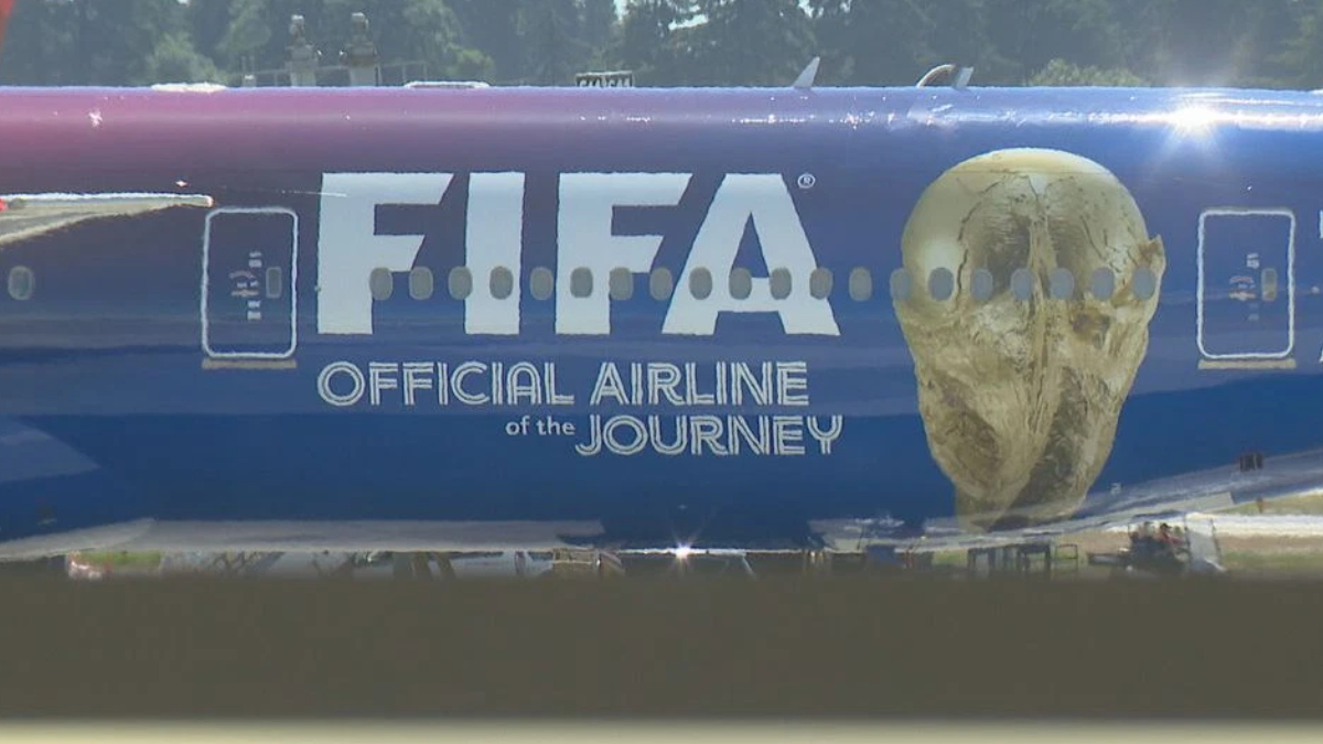 Blue airplane fuselage with a large 'FIFA' logo and a gold skull-like figure on the nose, plus the text 'Official Airline of the Journey'.