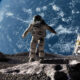 Astronaut in a spacesuit stands on the Moon's rocky surface with Earth visible in the background and a lunar lander nearby.