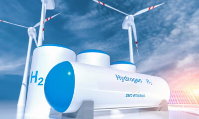 Hydrogen storage tanks with blue lids, wind turbines in the background, highlighting zero-emission energy from H2.