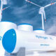Hydrogen storage tanks with blue lids, wind turbines in the background, highlighting zero-emission energy from H2.