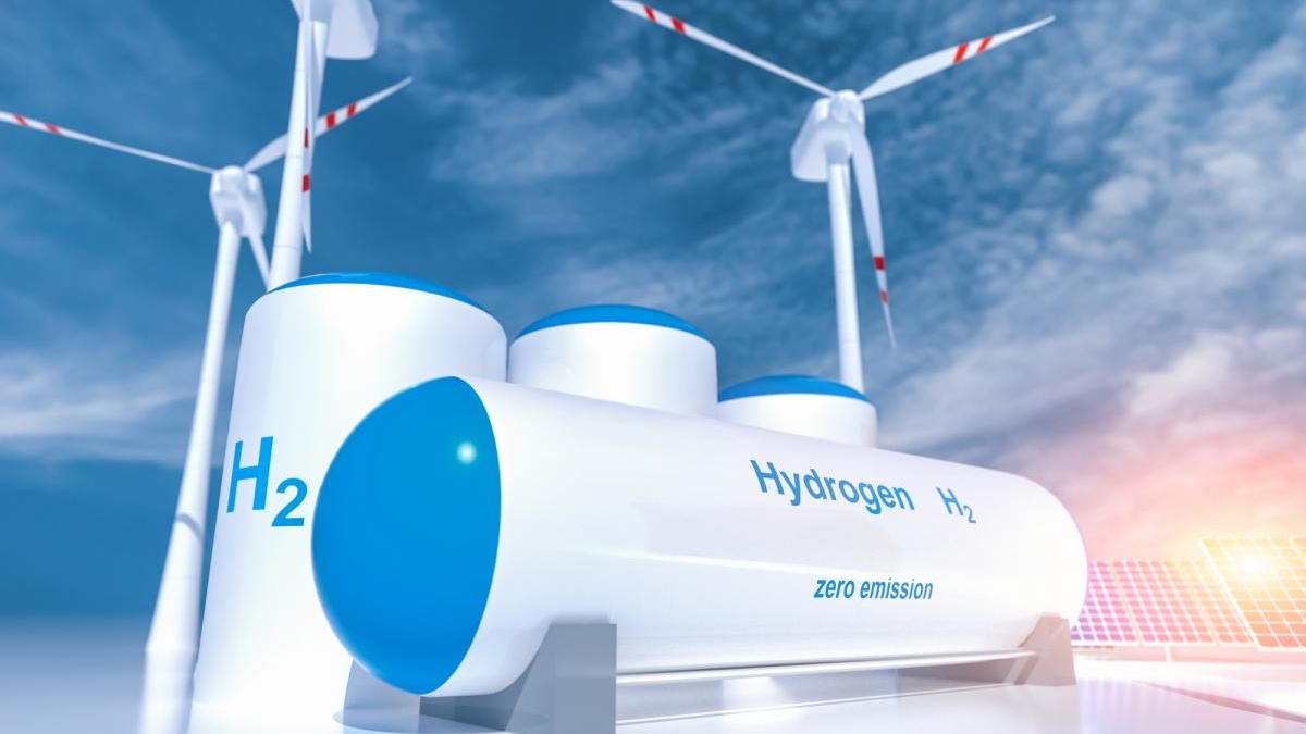Hydrogen storage tanks with blue lids, wind turbines in the background, highlighting zero-emission energy from H2.