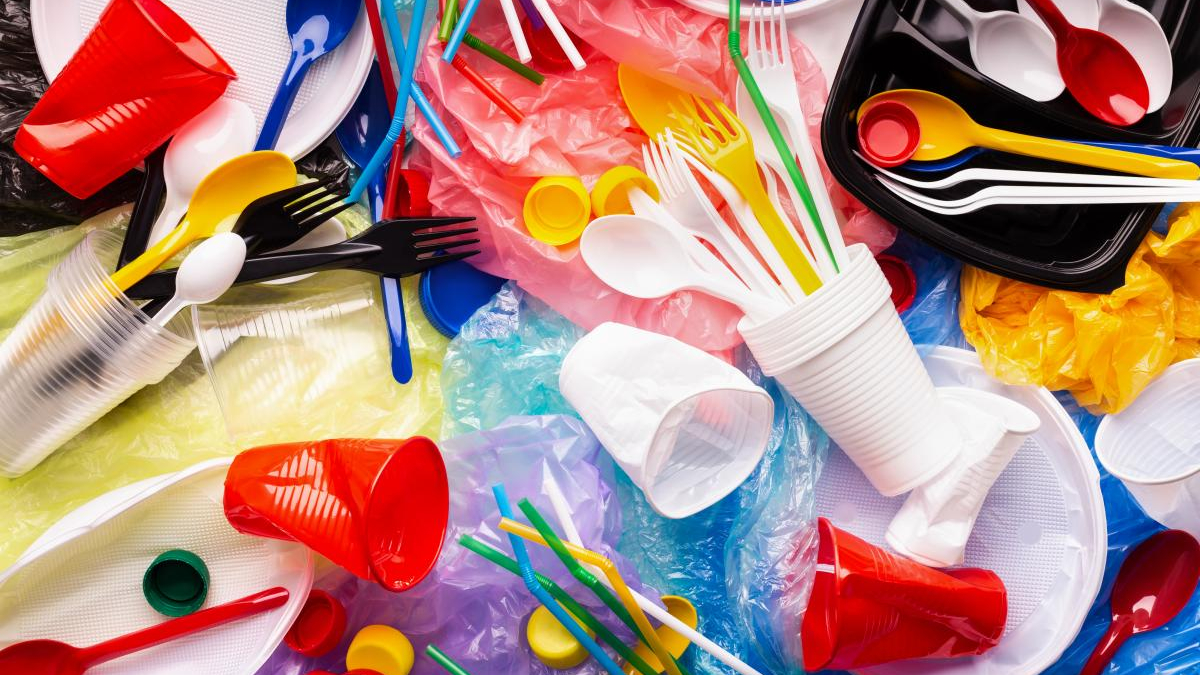 Pile of colorful plastic waste with cups, utensils, straws and bags scattered everywhere, highlighting single-use plastics.