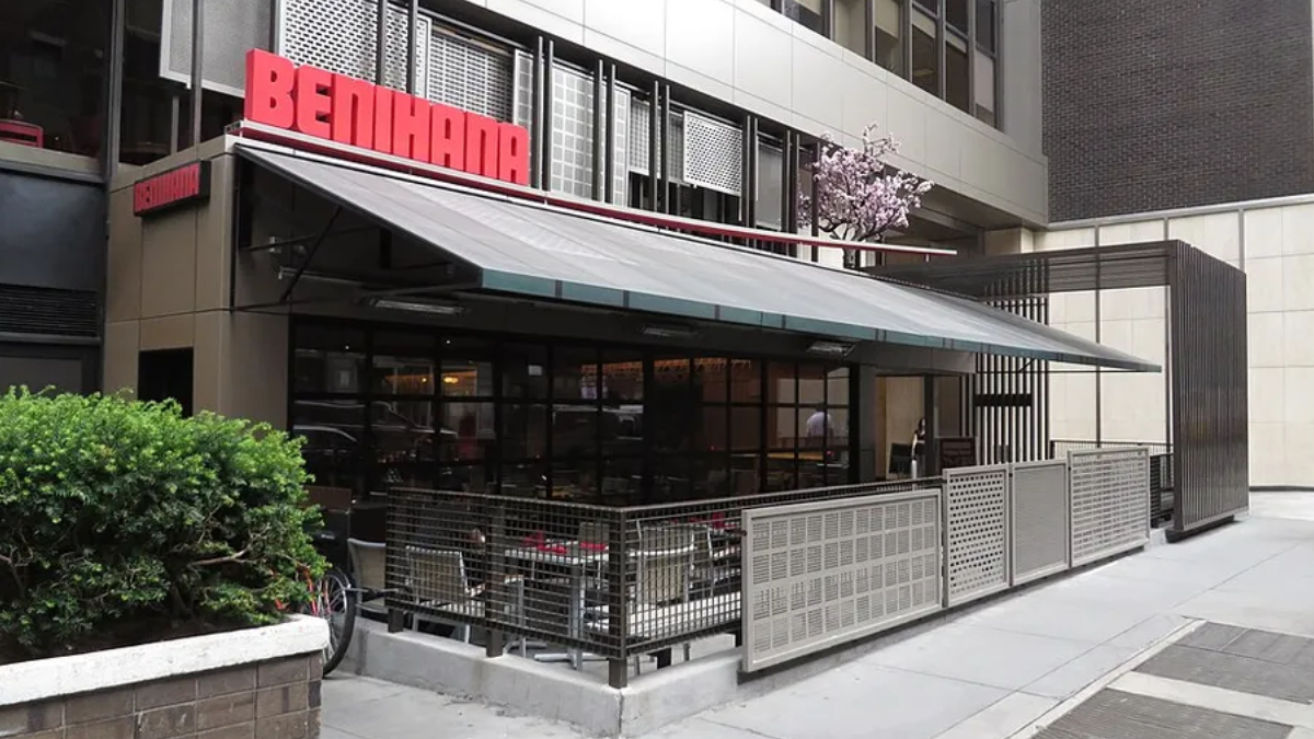 Exterior of a Benihana restaurant with outdoor seating under a large white awning/terrace.
