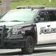 Kent Police SUV, black and white patrol vehicle with light bar on top and bold 'POLICE' lettering on the side, driving on a road