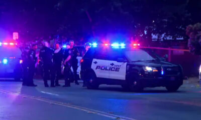 Nighttime street scene with Kent Police patrol SUV and multiple officers near flashing blue and red lights behind a taped area.
