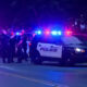 Nighttime street scene with Kent Police patrol SUV and multiple officers near flashing blue and red lights behind a taped area.