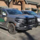 Two sheriff patrol SUVs with front-end damage parked in a lot outside brick buildings.