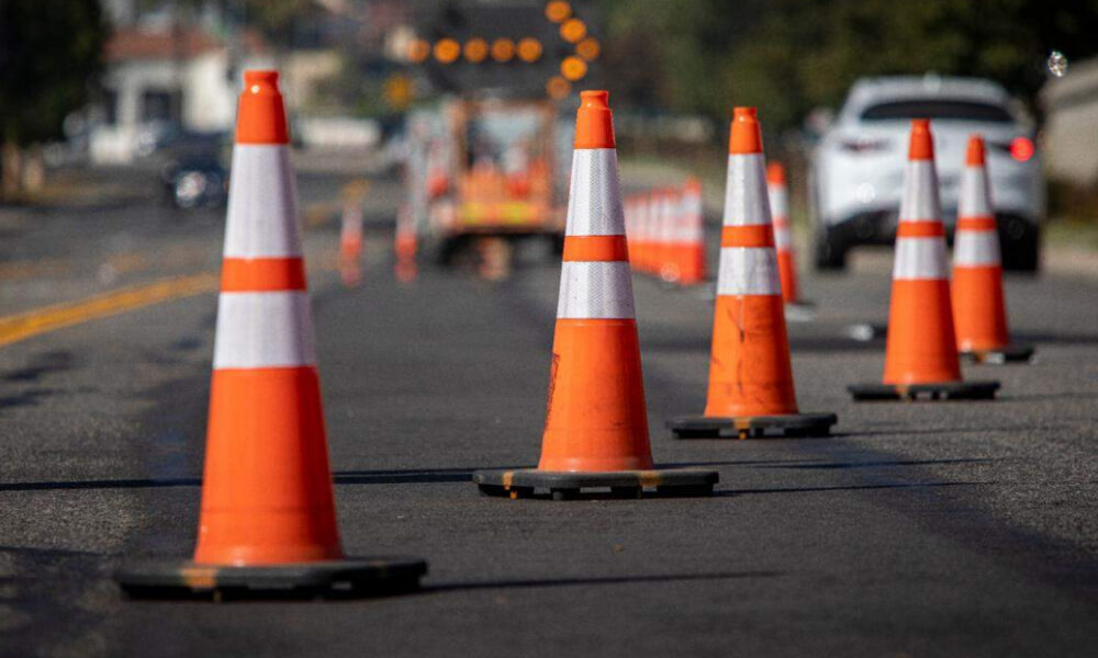 Row of orange traffic cones guiding traffic on a paved road at a construction site.