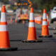 Row of orange traffic cones guiding traffic on a paved road at a construction site.