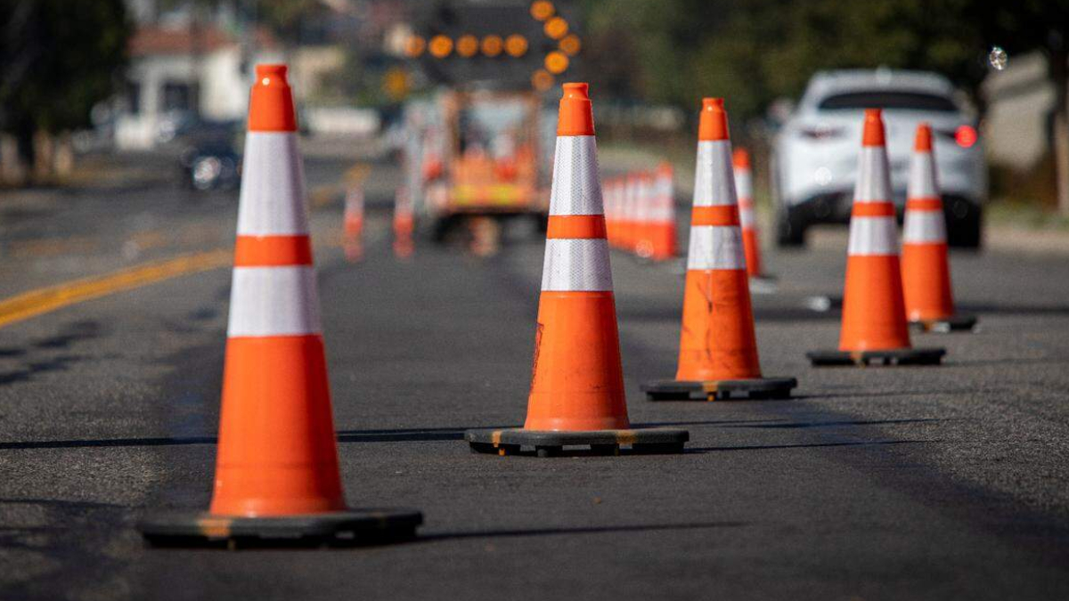 Row of orange traffic cones guiding traffic on a paved road at a construction site.