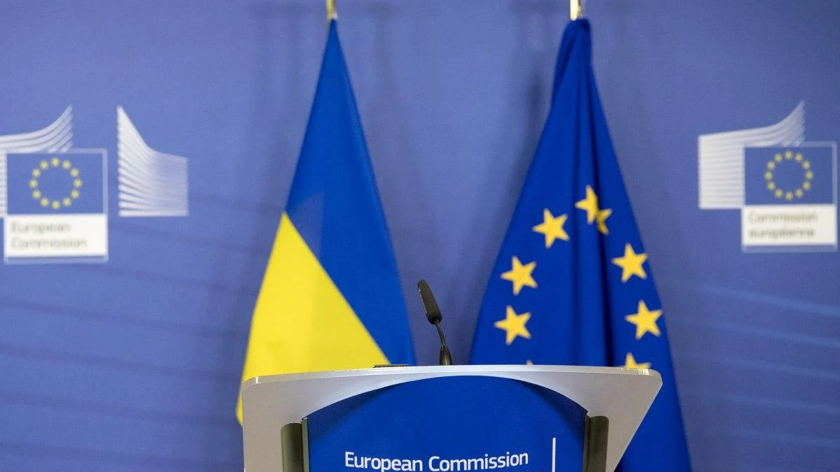 Podium at a European Commission press event with Ukrainian and EU flags in the background.
