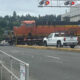 Orange BNSF locomotive crossing a street, with a white pickup truck in front and a worker in a high-visibility vest nearby.