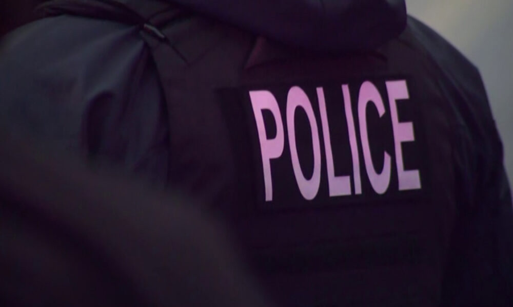 Back view of a police officer wearing a dark jacket with the word POLICE visible on the back