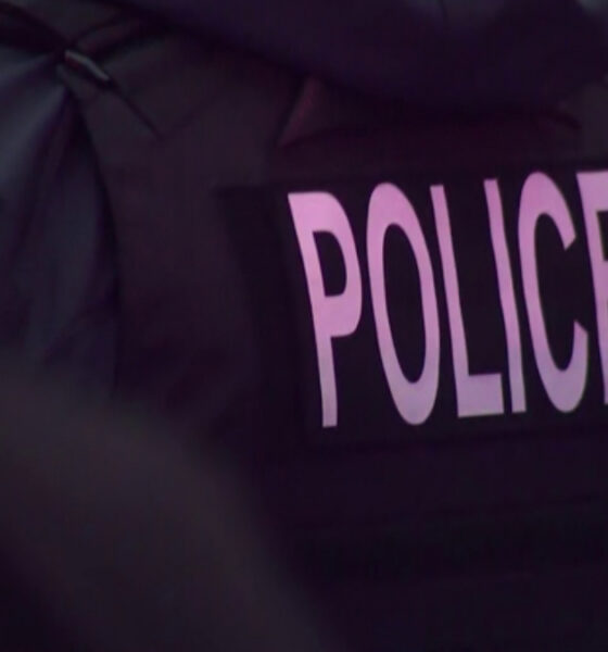 Back view of a police officer wearing a dark jacket with the word POLICE visible on the back