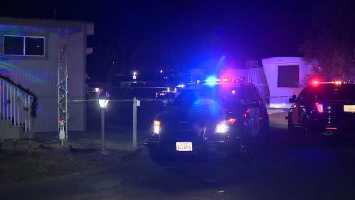 Police cars with blue and red lights at night in a residential area, yellow tape cordoning off the scene.