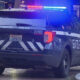 Seattle Police SUV with flashing red and blue lights parked on a city street, rear view shows 'SEATTLE POLICE' lettering and striped rear design.
