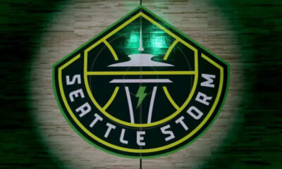 Seattle Storm team logo: a shield-shaped emblem with a green and yellow border, featuring a stylized flying saucer and a lightning bolt with 'Seattle Storm' text around the edge