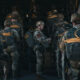 Soldiers in camouflage with backpacks lining up to board a large military transport aircraft via its open rear ramp.