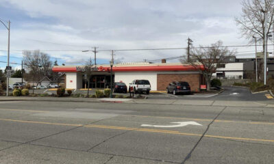 Wide street view of a Kwik Trip convenience store with a red awning, white facade, and parked cars in the lot.