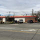 Wide street view of a Kwik Trip convenience store with a red awning, white facade, and parked cars in the lot.