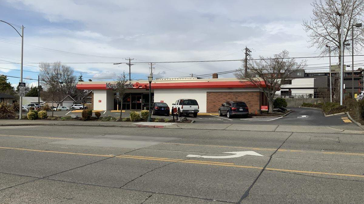 Wide street view of a Kwik Trip convenience store with a red awning, white facade, and parked cars in the lot.