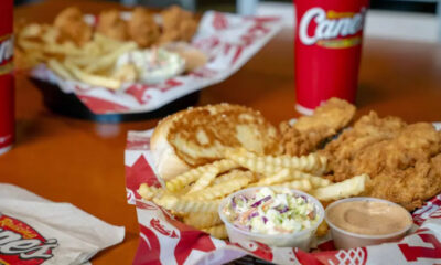 Fried chicken, fries, onion rings, coleslaw, and two dipping sauces on a red-tray meal at a fast-food joint.