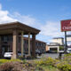 Exterior view of Oasis Inn hotel with a covered driveway and parked cars on a sunny day.