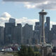 Seattle skyline with the Space Needle towering over downtown against a blue sky with scattered clouds.