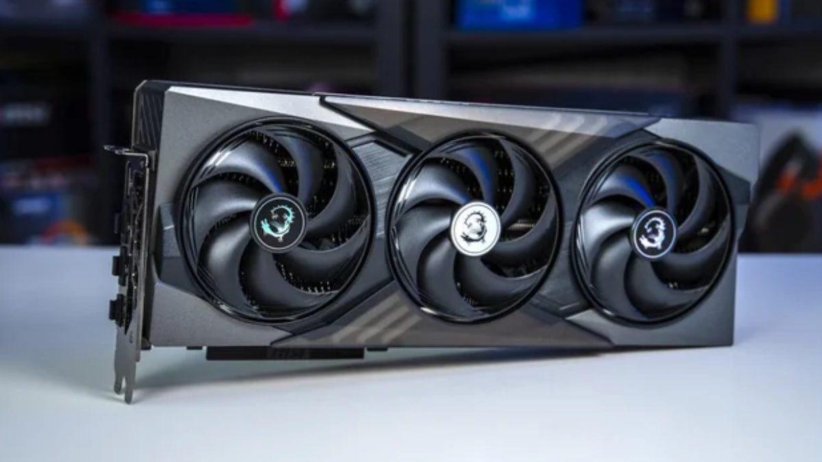 MSI triple‑fan graphics card with a black and gray shroud resting on a white table, showing three cooling fans with MSI dragon logos at the center caps