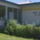 Exterior of City Hall Oak Harbor with glass doors and blue columns, surrounded by greenery in front.
