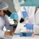 Two scientists in white lab coats work in a split-view: one looks through a microscope, the other uses a pipette to transfer liquid.