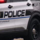 Puyallup Police SUV parked on a street with bold POLICE lettering and city emblem on the door, officer visible nearby legs only.