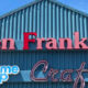 Storefront with a teal metal exterior and large red Ben Franklin sign above a blue and white 'Frame Shop' sign and cursive 'Crafts' lettering beneath.