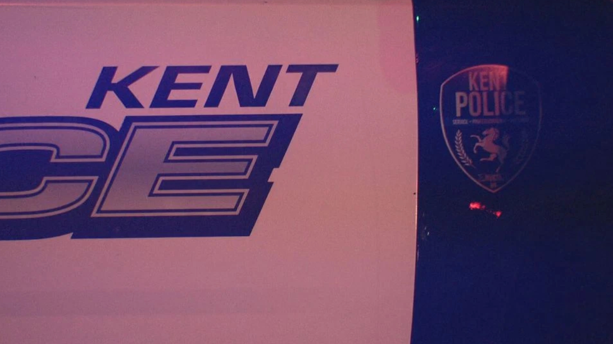 Sign with 'KENT' and large stylized letters beside a Kent Police shield logo on a dark background.