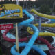 Aerial view of Wild Waves theme park water slides in bright blue, yellow, red, and purple tubes with a Coca-Cola sign nearby.
