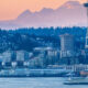 Seattle skyline at sunset with the Space Needle, water in the foreground, and a ferry on the bay