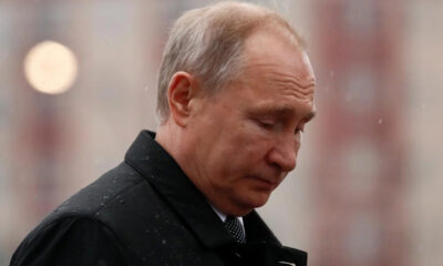 Man in a dark coat looking downward in light rain.