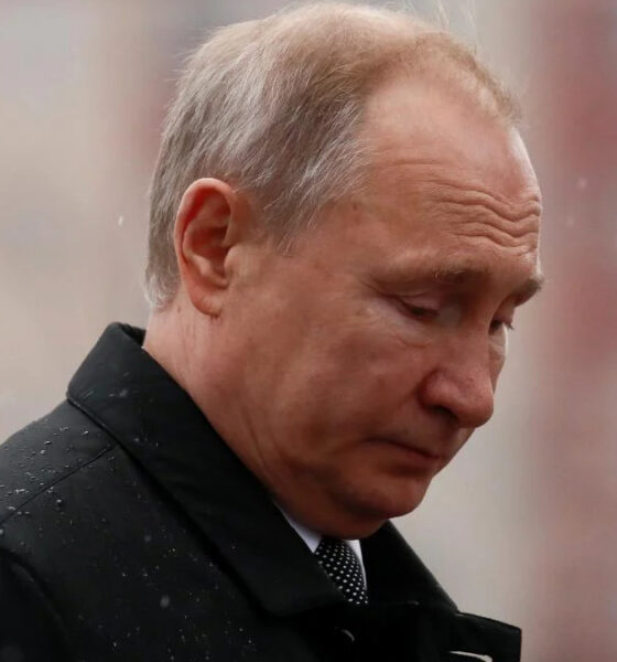 Man in a dark coat looking downward in light rain.