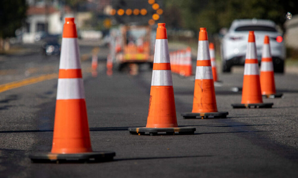 Row of orange and white traffic cones lining a road to mark a construction zone on a city street.