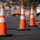 Row of orange and white traffic cones lining a road to mark a construction zone on a city street.