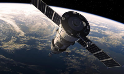 Satellite with large solar panels orbiting Earth, curving horizon and atmosphere visible below