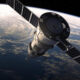 Satellite with large solar panels orbiting Earth, curving horizon and atmosphere visible below