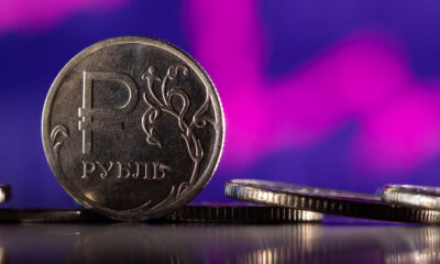 Close-up of a 1 ruble coin standing on edge with a purple blurred background on the shiny surface.