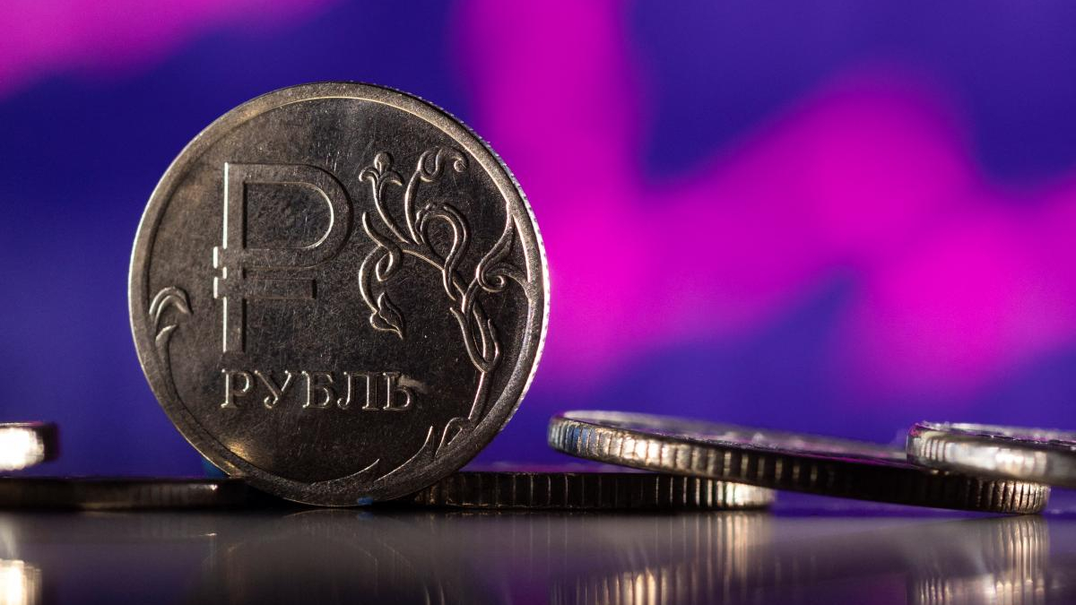 Close-up of a 1 ruble coin standing on edge with a purple blurred background on the shiny surface.
