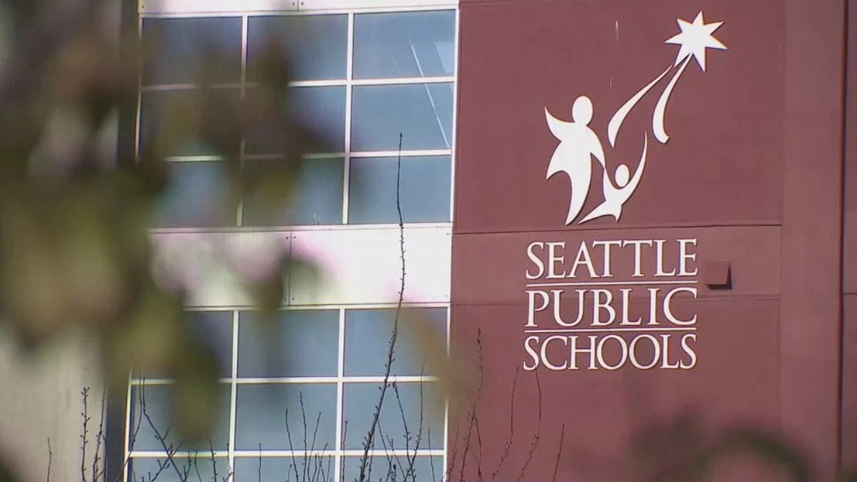 Seattle Public Schools building facade with logo and sign reading 'Seattle Public Schools' in maroon panel.