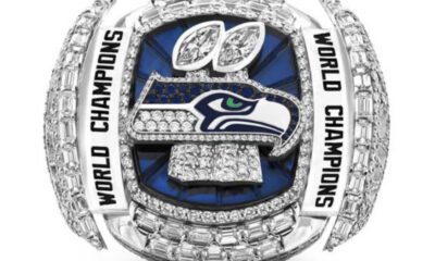 Diamond-encrusted Seattle Seahawks World Champions ring with blue background and surrounding “World Champions” inscriptions.