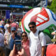 Crowd at an outdoor festival with a giant inflatable soccer ball centerpiece in the background.
